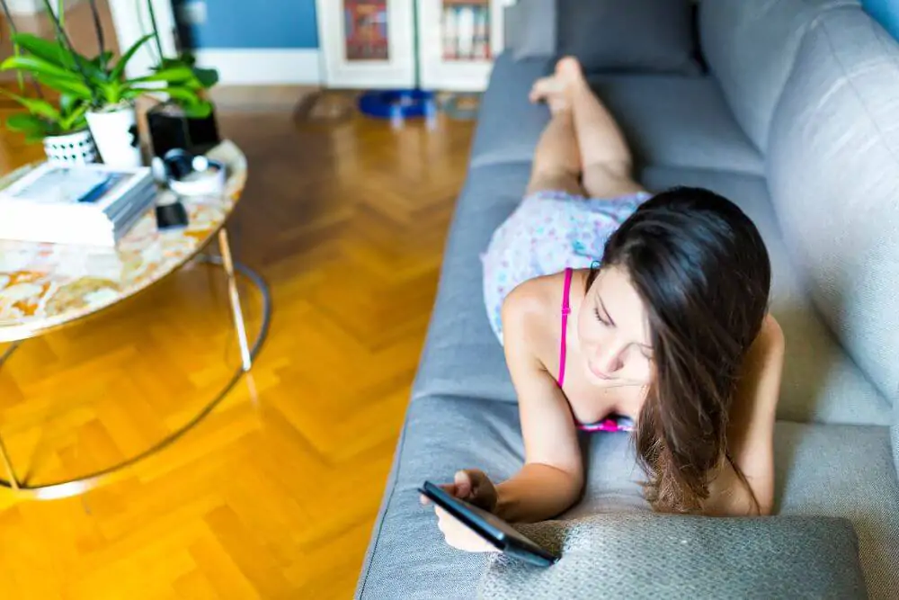 Frau liest E-Book auf Sofa